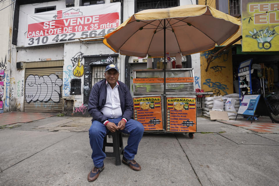 Ángel Bruges, from Venezuela, poses for a portrait at his empanada stand in Bogota, Colombia, Wednesday, Feb. 22, 2023. Bruges and his wife began selling empanadas from a cart when they moved here in 2019, parlayed that cart into a shop and three larger carts and used some of their earnings to relocate their daughter to Bogota last year. (AP Photo/Fernando Vergara)