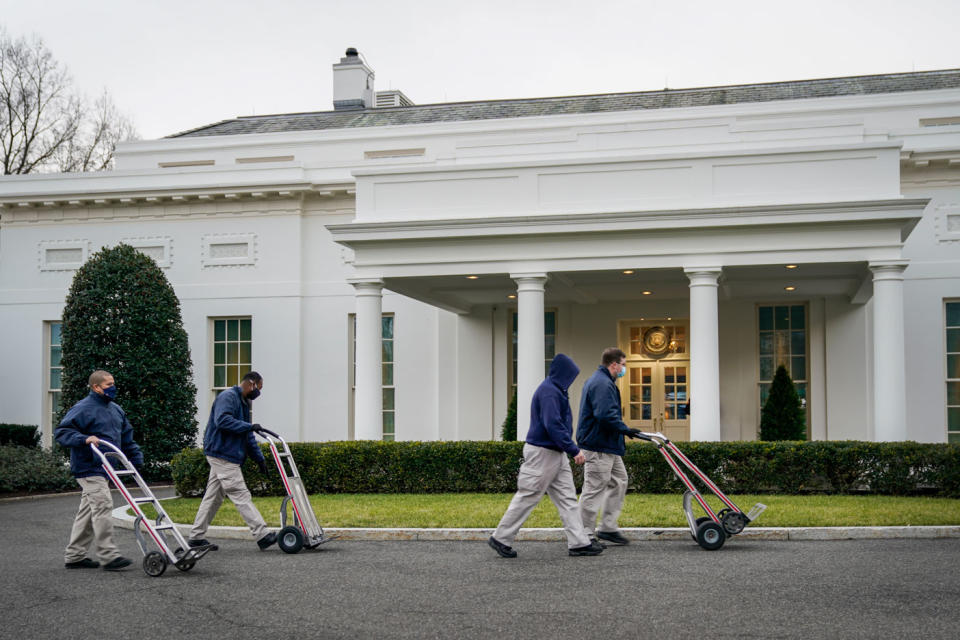 Pictured are people pushing moving trolleys outside the White House.