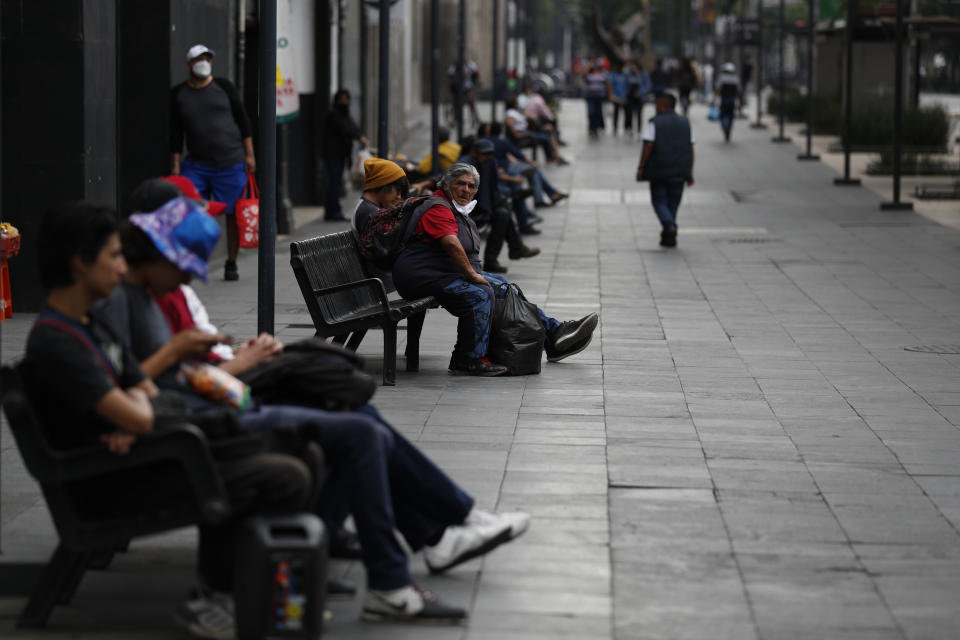 People enjoy the fresh air on benches along Juarez Avenue in central Mexico City, Sunday, May 31, 2020. Mexico's capital plans to reopen certain sectors of the economy and public life beginning Monday, despite the city still being in the most serious "red light" phase of the coronavirus pandemic. (AP Photo/Rebecca Blackwell)