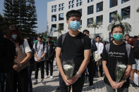 Protesters hold flowers to remember Chow Tsz-Lok after protesters disrupted a graduation ceremony at the University of Science and Technology in Hong Kong on Friday, Nov. 8, 2019. The ceremony was cut short, and black-clad masked students turned the stage into a memorial for Chow who fell off a parking garage after police fired tear gas during clashes with anti-government protesters and died Friday. (AP Photo/Kin Cheung)