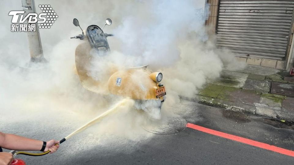 電動車突然竄出大量白煙，警員持滅火器撲救。（圖／TVBS）