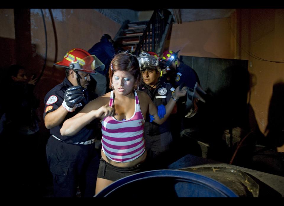 Firefighters help rescue a prostitute after she became trapped in a tunnel from an offensive against human trafficking at the Super Frontera bar late on April 21, 2012, in Guatemala City. (Photo credit: Johan Ordonez/AFP/Getty Images)