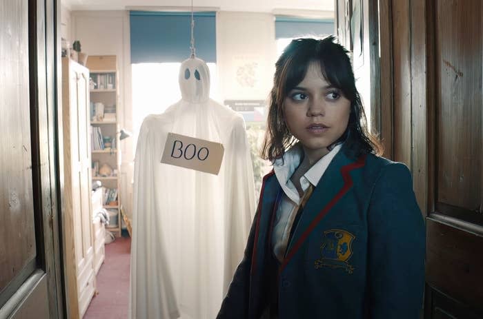 Jenna Ortega in a school uniform with a ghost decoration with a "Boo" sign in "Beetlejuice Beetlejuice"