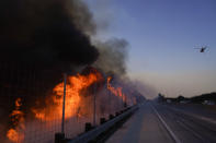 The Blue Ridge Fire burns along the 71 state highway Tuesday, Oct. 27, 2020, in Chino Hills, Calif. Crews tried to beat back two out-of-control wildfires in Southern California on Tuesday that have kept tens of thousands of people out of their homes even as another round of dangerous fire weather raises the risk for flames erupting across the state. (AP Photo/Jae C. Hong)