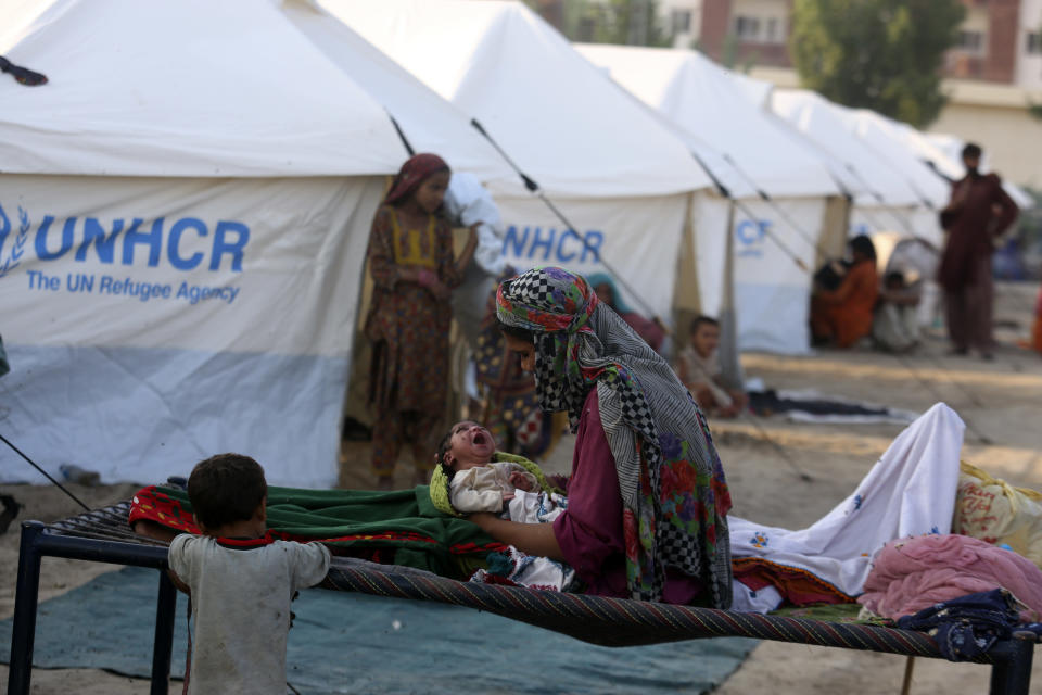 A displaced woman hold her newborn baby as she takes refuge at a temporary tent housing camp for flood victims organized by the UN Refugee Agency (UNHCR), in Sukkur, Pakistan, Saturday, Sept. 10, 2022. Months of heavy monsoon rains and flooding have killed over a 1000 people and affected 3.3 million in this South Asian nation while half a million people have become homeless. (AP Photo/Fareed Khan)