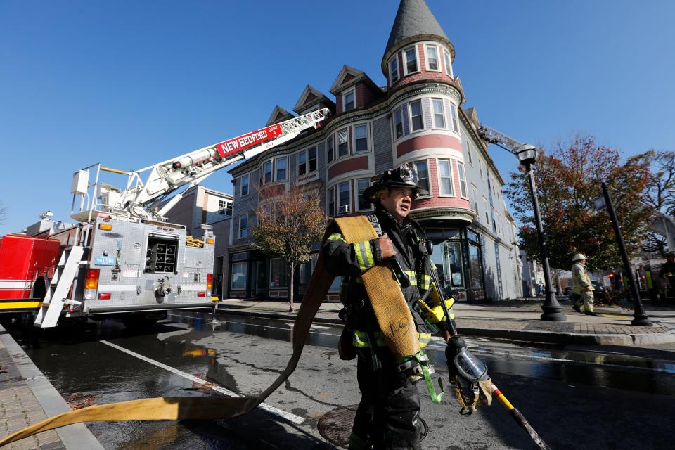 New Bedford firefighter Mark Pacheco carries the hose after  responding to a fire at 1168 Acushnet Avenue in New Bedford.