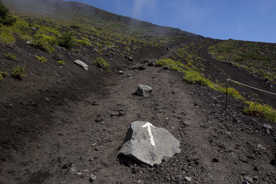 In this Thursday, Aug. 29, 2013 photo, an arrow painted on a rock points the way on a trail along the slopes of Mount Fuji in Japan. The Japanese cheered the recent recognition of Mount Fuji as a UNESCO World heritage site, though many worry that the status may worsen the damage to the environment from the tens of thousands who visit the peak each year. (AP Photo/David Guttenfelder)