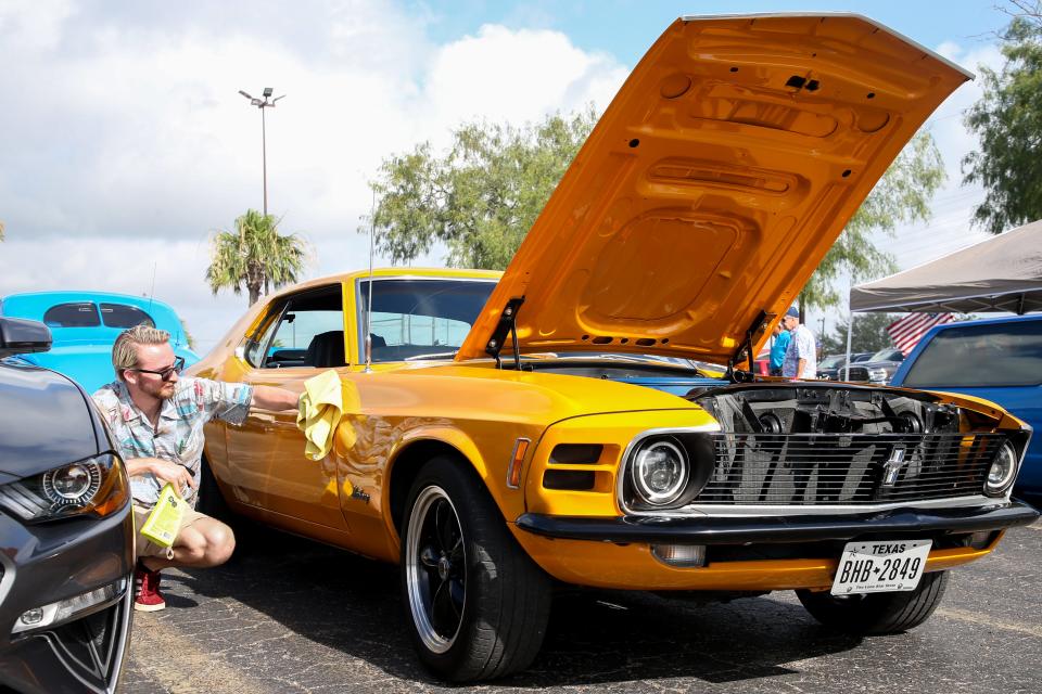 Evan Pruski wipes down his 1970 Ford Mustang Coupe at the 29th annual Coastal A's & Rod's Fun Run car show Saturday, May 28, 2022.