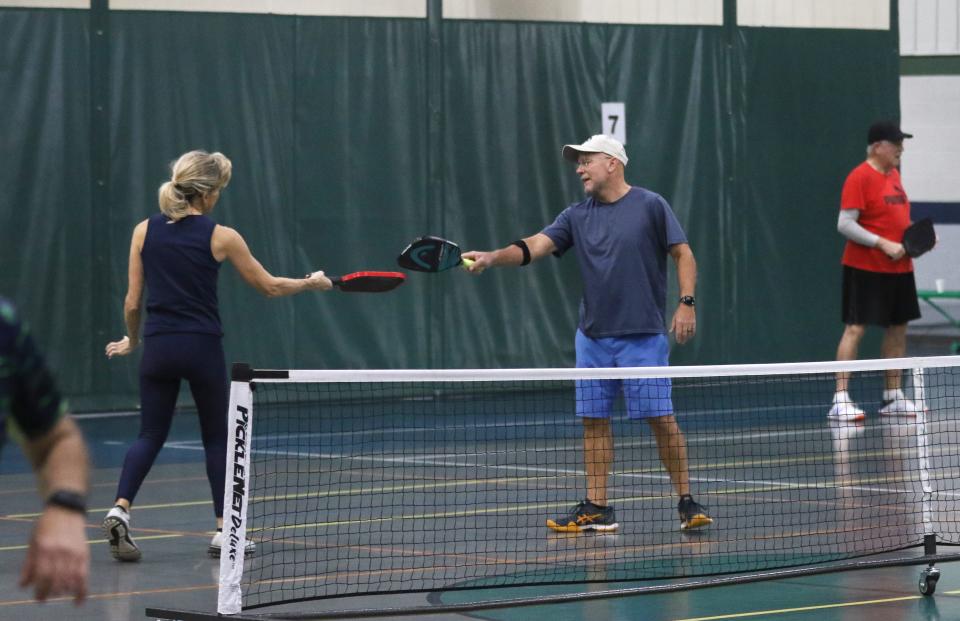 Daphnie France and Jim Gorndt touch paddles after a point during a pickleball match at Kids America recently.