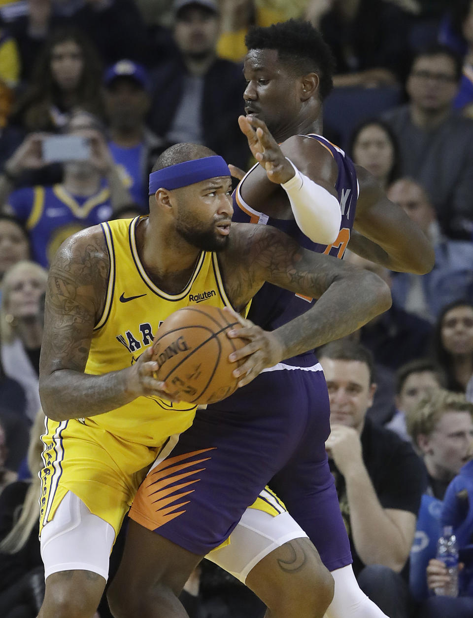 Golden State Warriors center DeMarcus Cousins, left, drives to the basket against Phoenix Suns center Deandre Ayton during the first half of an NBA basketball game in Oakland, Calif., Sunday, March 10, 2019. (AP Photo/Jeff Chiu)