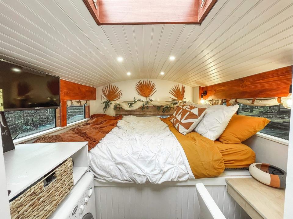 The bedroom on the van, with a queen-sized bed and orange/yellow colors