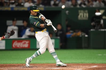 Mar 17, 2019; Tokyo, Japan; Oakland Athletics left fielder Khris Davis (2) hits a double during the third inning against the Nippon Ham Fighters at Tokyo Dome. Mandatory Credit: Darren Yamashita-USA TODAY Sports