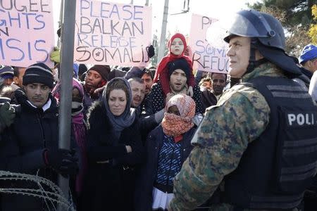 Migrants protestt in front of a Macedonian police officer after trying to cross the border from Greece into Macedonia, near Gevgelija, Macedonia, November 28, 2015. REUTERS/Stoyan Nenov