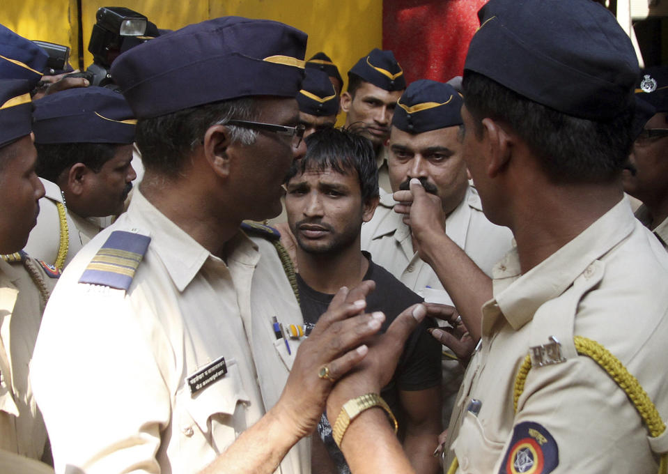 Police officials escort one of the four convicts in a gang rape case to a court in Mumbai, India, Friday, April 4, 2014. An Indian court on Friday sentenced to death three men who raped a photojournalist inside an abandoned textile mill in the financial hub of Mumbai last year. A fourth defendant was sentenced to life in prison, Nikam said. (AP Photo)