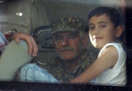 A fighter loyal to President Bashar al Assad and a child are seen in a bus as they are evacuated from the villages of al-Foua and Kefraya, Syria July 19, 2018. REUTERS/Khalil Ashawi