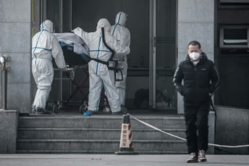 Medical workers carry a patient into a hospital for patients infected with the new coronavirus strain in Wuhan, China