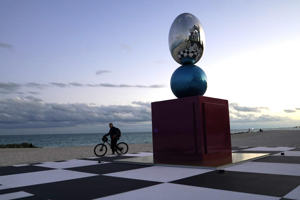 A cyclist goes past an art installation titled, "Hall of Visions," by artist Pilar Zeta of Argentina, on the beach at the Faena Hotel during Miami Art Week, Tuesday, Nov. 30, 2021, in Miami Beach, Fla. Miami Art Week is an annual event centered around the Art Basel Miami Beach fair. (AP Photo/Lynne Sladky)