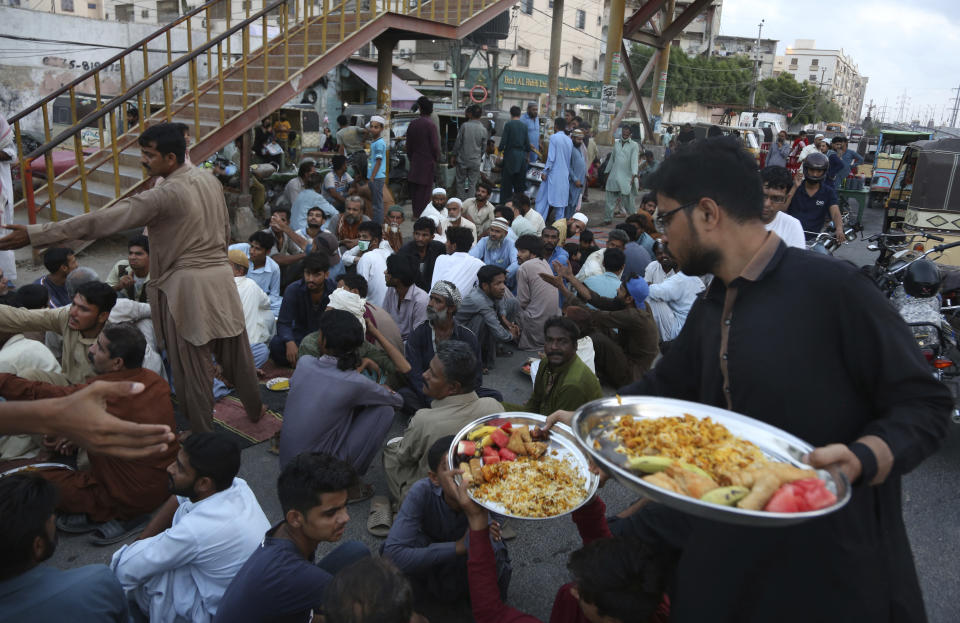 Volunteers distribute food among people to break their fast during the Muslims fasting month of Ramadan after the government relaxed a weeks-long lockdown that was enforced to curb the spread of the coronavirus on Tuesday, May 12, 2020. (AP Photo/Fareed Khan)