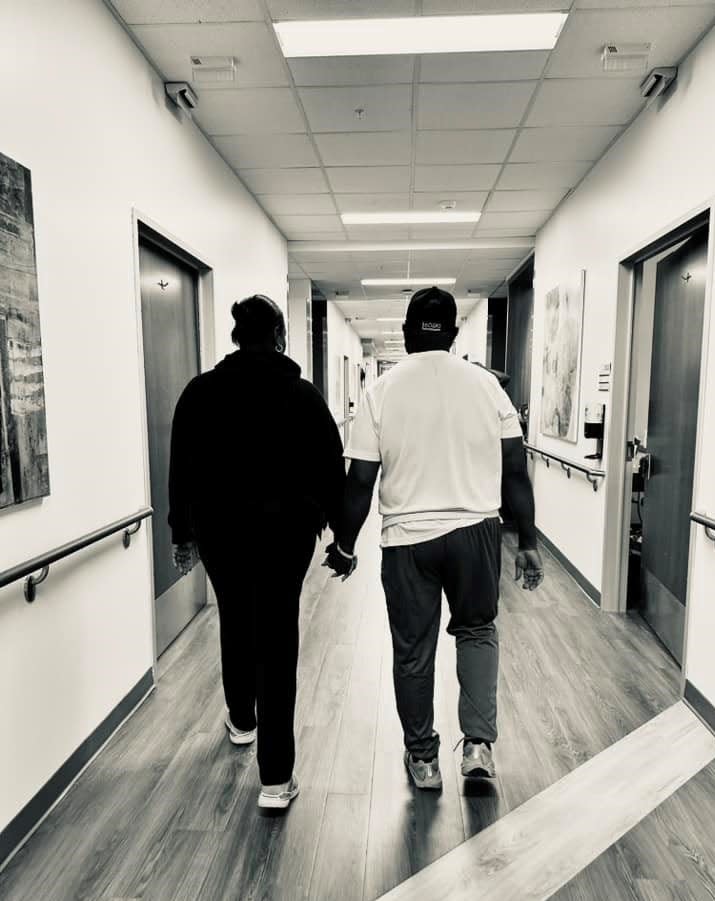 Lakesha and Greg Burton, walking down a hall at Brooks Rehabilitation, where he's recovering from a stroke suffered Sept. 29.