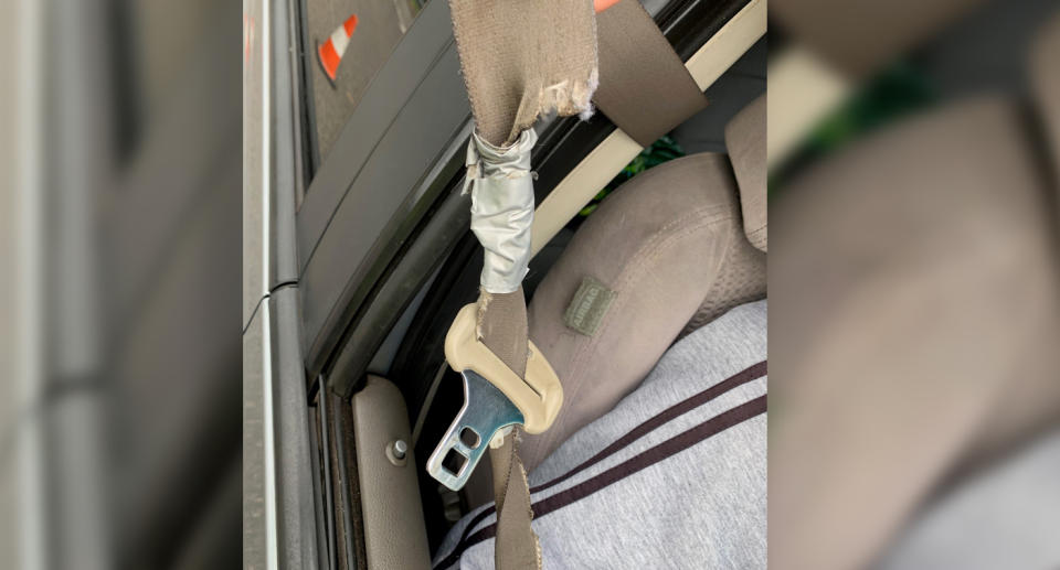 An old brown frayed seatbelt tapped together with duct tape.