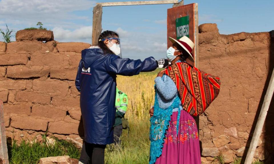 A government worker checks the temperature of a Quechua indigenous peasant arriving to vote in the village of Capachica, in Puno, Peru.