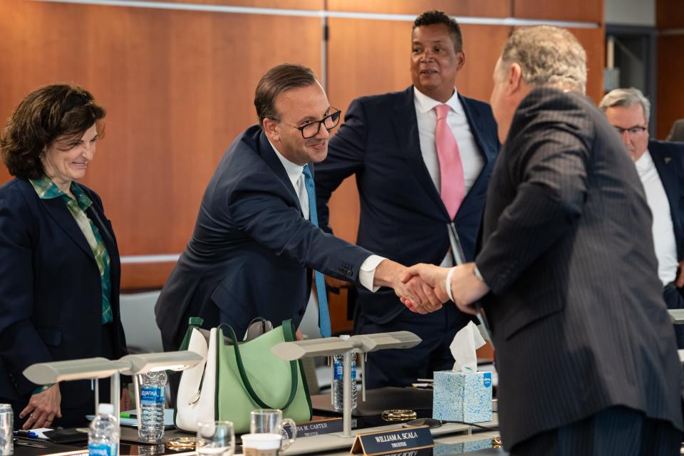 R.J. Nemer, dean of UA's College of Business and the new university president, stands beside Board Chairman Lewis Adkins and shakes hands with board of trustees member Michael Saxon after the announcement of his new role Wednesday.