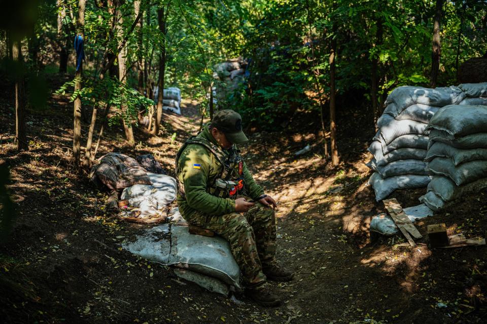 A Ukrainian soldier reads news on his mobile phone on the front line in Southern Ukraine on October 8, 2022