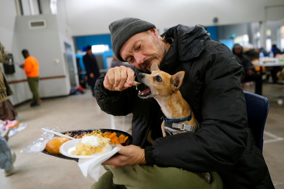 Gemini Lyons feeds some turkey to his dog Little Bit on Wednesday, Nov. 23, 2022, during a Thanksgiving meal at the Homeless Alliance.