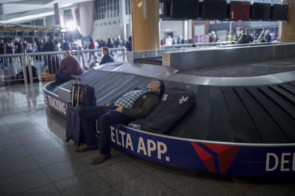 Exhausted: a passenger waits at Atlanta airport (AP)