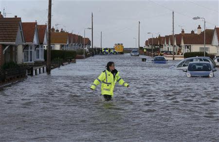 An emergency rescue service worker walks through flood water in a residential street in Rhyl, north Wales December 5, 2013. REUTERS/Phil Noble