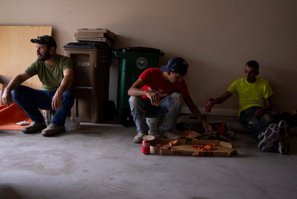 Juan Pedro Muñoz, 45, left, Johnny Barcenas, 24, center, and  Juan Barcenas, 45, right, take a lunch break while working on renovating the floor of a home in Austin on July 7, 2023. “We’ve got breaks all day,” Muñoz said. “It’s still very hot and the guys need to drink water and everything.”