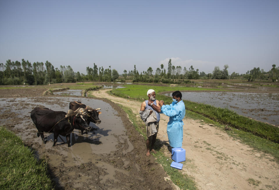 FILE - In this June 10, 2021, file photo, a health worker administers the AstraZeneca vaccine for COVID-19 to a Kashmiri farmer at Minnar village, north of Srinagar, Indian controlled Kashmir. Starting June 21, 2021, every Indian adult can get a COVID-19 vaccine dose for free that was purchased by the federal government. The policy reversal announced last week ends a complex system of buying vaccines that worsened inequities in accessing vaccines. India is a key global supplier of vaccines and its missteps have left millions of people waiting unprotected. The policy change is likely to address inequality but questions remain and shortages will continue. (AP Photo/Mukhtar Khan, File)