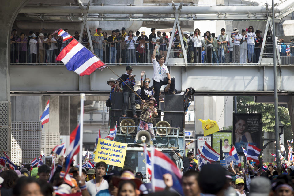 Anti-government protestors wave national flags march through the Pathumwan district, Sunday, Jan. 12, 2014, in Bangkok, Thailand. Anti-government protesters took over key intersections in Thailand's capital Monday, halting much of the traffic into Bangkok's central business district as part of a months-long campaign to thwart elections and overthrow the democratically elected prime minister. (AP Photo/John Minchillo)
