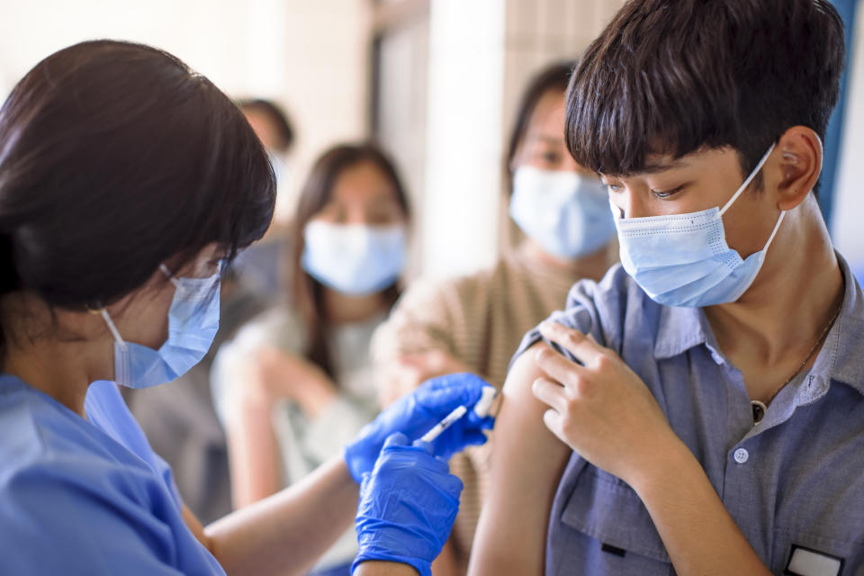 Doctor injecting vaccine for  students in high school