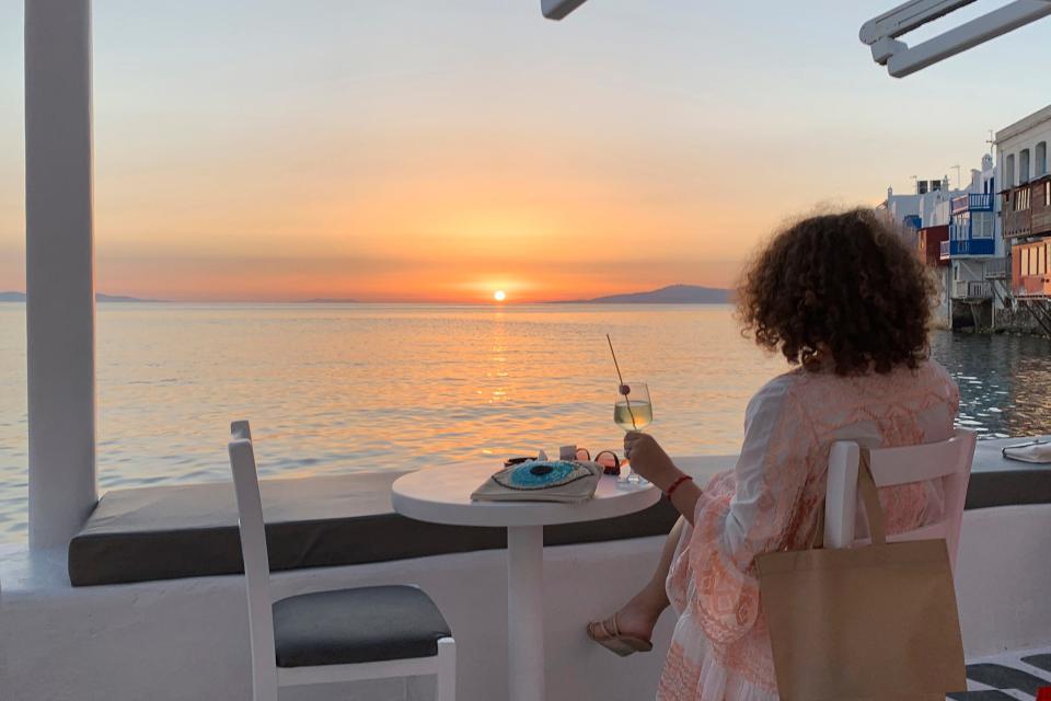 A visitor watches the sunset at a bar on the island of Mykonos, Greece on  June 9, 2020. Greek Tourism Minister Vassilis Kikilias said the country plans to remain open until the end of the tourist season.