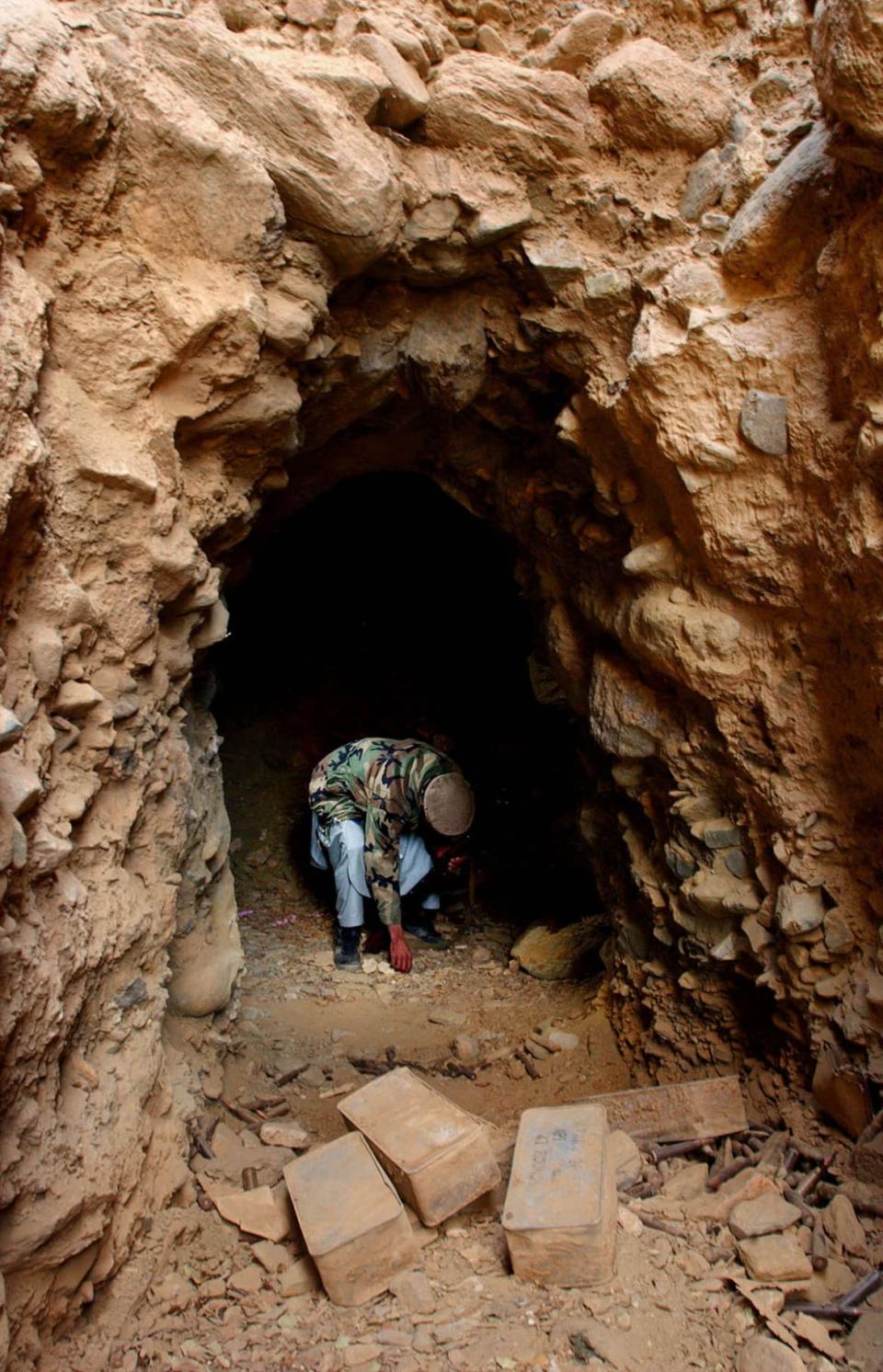 <div class="inline-image__caption"><p>A mujahadeen soldier picks up an item at the entrance to a former Al-Qaeda cave December 24, 2001 in Tora Bora, Afghanistan. </p></div> <div class="inline-image__credit">Chris Hondros/Getty</div>