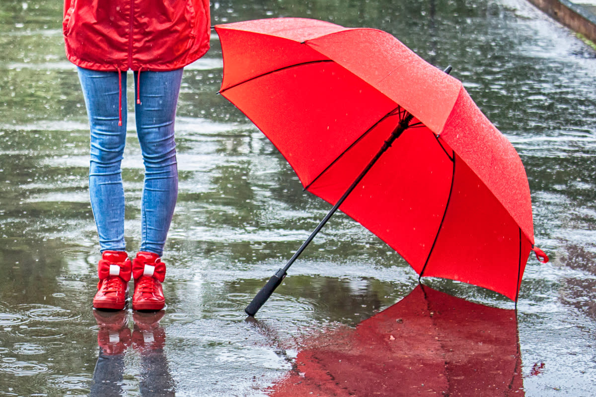 A red umbrella sits on the ground as it rains.