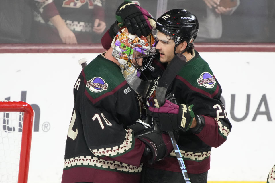 Arizona Coyotes center Jack McBain celebrates with goaltender Karel Vejmelka (70) after the team's win over the Ottawa Senators in an NHL hockey game Tuesday, Dec. 19, 2023, in Tempe, Ariz. (AP Photo/Rick Scuteri)