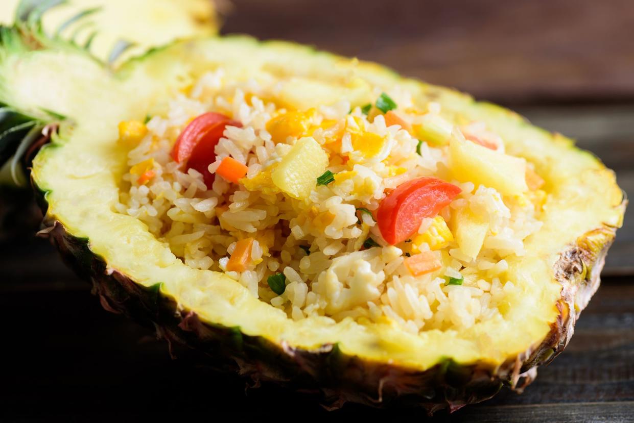 Thai food, pineapple fried rice in pineapple fruit bowl on wooden background