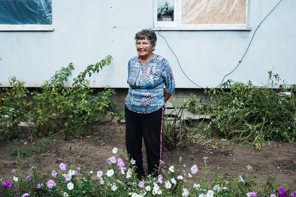 Halyna, 84, photographed by her damaged windows in a residential building that was shelled the previous night in Velyka Novosilka, Donetsk Oblast on Sept. 11, 2023. (Anastasia Vlasova / The Kyiv Independent)