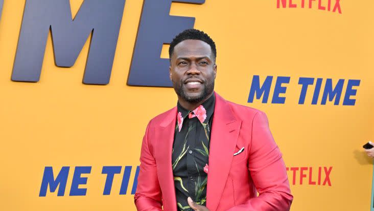 kevin hart posing for photos in a pink suit at a premiere event