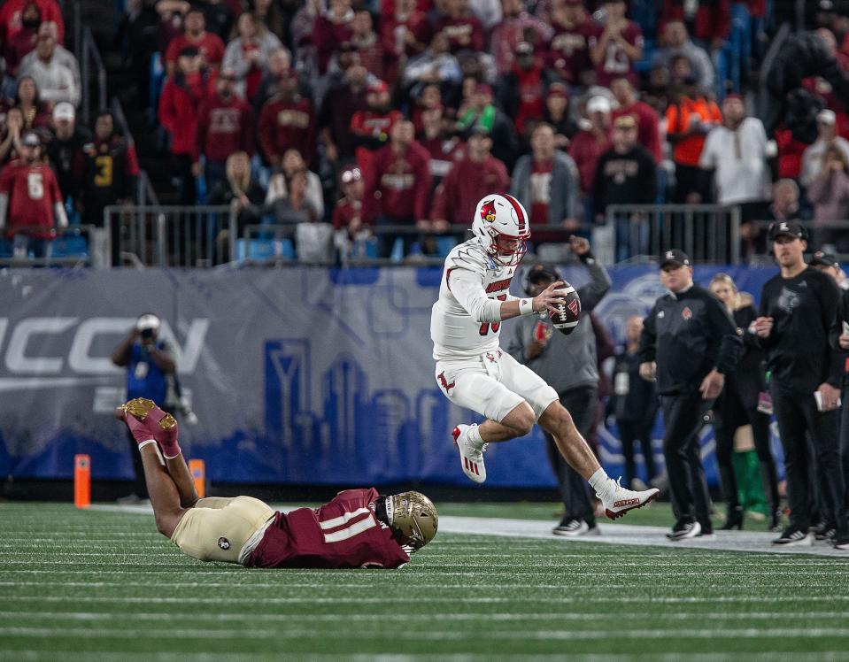 Louisville quarterback Jack Plummer (13) jumped to elude the grasp of FSU's Patrick Payton (11) during first half action as the Louisville Cardinals faced off against the Florida State Seminoles in the 2023 ACC Championship game at Bank of America Field in Charlotte, NC, on Saturday, Dec. 2, 2023.