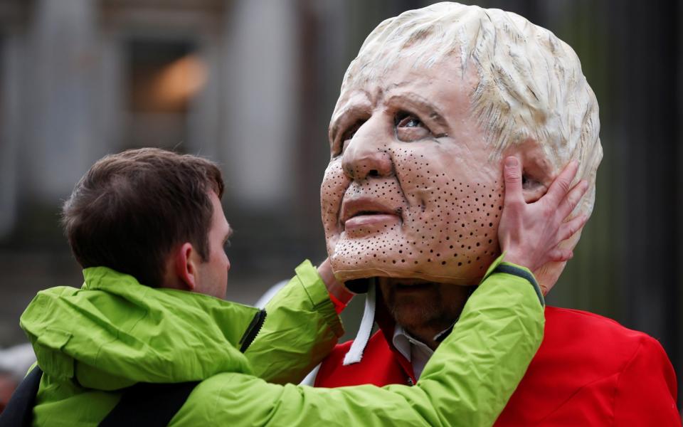 A man adjusts the 'Big Head' of Boris Johnson worn by an Oxfam activist - Reuters