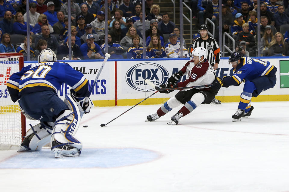 Colorado Avalanche's Nikita Zadorov (16), of Russia, handles the puck in front of St. Louis Blues' Jay Bouwmeester (19) as goaltender Jordan Binnington (50) protects the goal during the second period of an NHL hockey game Monday, Oct. 21, 2019, in St. Louis. (AP Photo/Scott Kane)