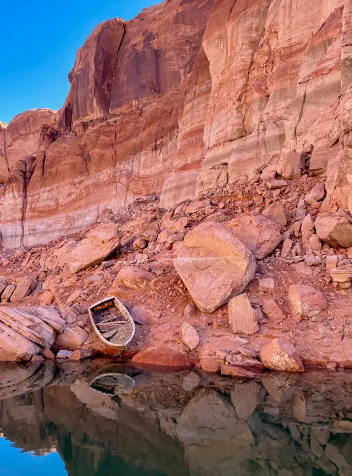 An abandoned and once-sunken boat sits along the shoreline of Lake Powell in this May 2022 file photo. The white ring above shows how high the water level was when the lake was full.