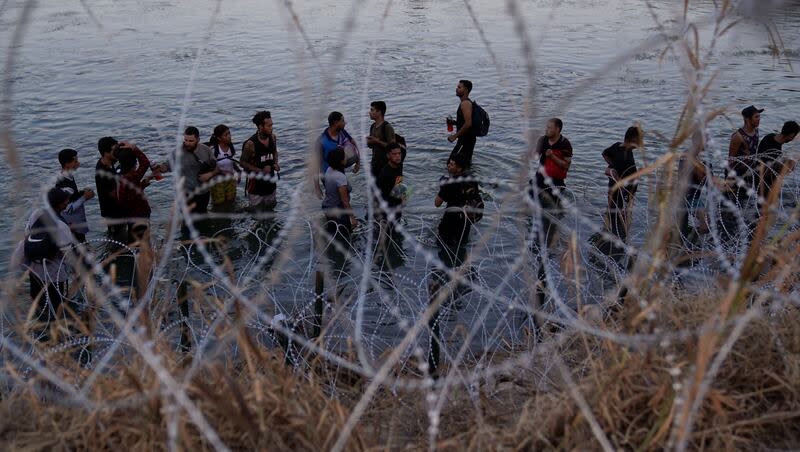 Migrants wait to climb over concertina wire after they crossed the Rio Grande and entered the U.S. from Mexico, Sept. 23, 2023, in Eagle Pass, Texas.