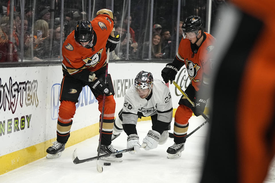 Los Angeles Kings defenseman Sean Walker, center, falls as he vies for the puck with Anaheim Ducks defenseman John Klingberg, left, and center Isac Lundestrom during the first period of an NHL hockey game Friday, Feb. 17, 2023, in Anaheim, Calif. (AP Photo/Mark J. Terrill)