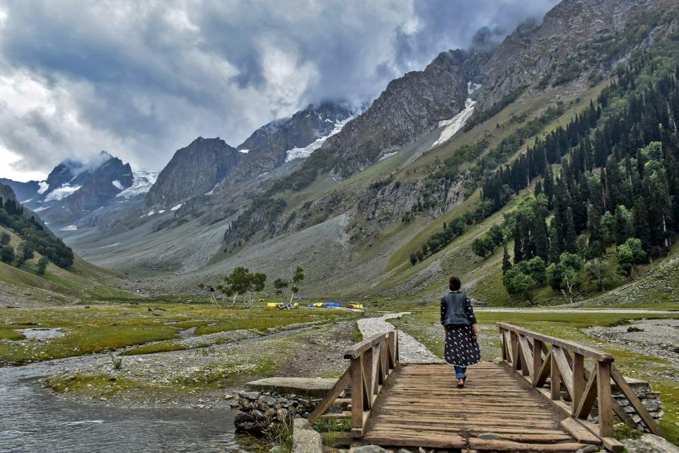 JAMMU AND KASHMIR, INDIA - 2019/07/28: A visitor walks through a foot bridge on a cloudy day at the tourist resort Sonamarg about 90kms from Srinagar, the summer capital of J&K, India. As the rains continued for the fourth day on Sunday, the skies remained cloudy in the second half of the day. The weather department has predicted more precipitation in many parts of the valley in the next 24 hours. (Photo by Saqib Majeed/SOPA Images/LightRocket via Getty Images)