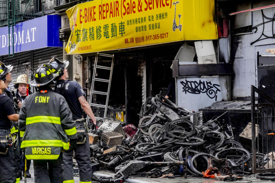 FILE - Firefighters and investigators go through the aftermath of a fire which authorities say started at an e-bike shop and spread to upper-floor apartments, Tuesday, June 20, 2023, in New York. New York City is receiving $25 million in emergency funding from the U.S. Department of Transportation to establish scores of new e-bike charging stations across the city. Mayor Eric Adams announced the funding Sunday, June 25. (AP Photo/Bebeto Matthews, File)