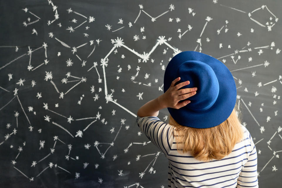 Rear view of young woman in striped shirt and hat looking at constellation in the shape of heart